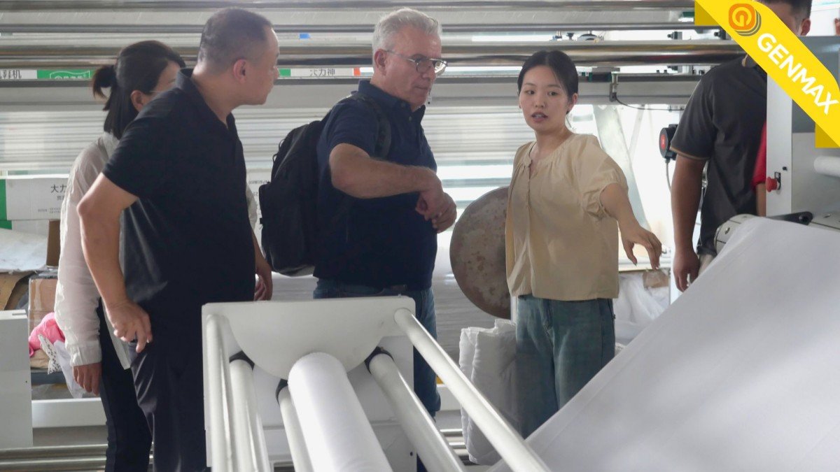 Mexican delegation from Puebla watching an industrial quilting machine in operation during their technical demonstration at the manufacturing plant.